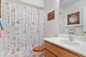 Bathroom with a shower with curtain, vanity, and toilet