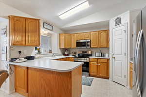 Kitchen with sink, lofted ceiling, kitchen peninsula, and appliances with stainless steel finishes