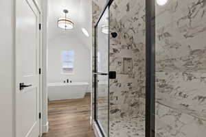 Bathroom with wood-type flooring, separate shower and tub, and vaulted ceiling