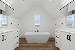 Bathroom featuring lofted ceiling, wood-type flooring, a bath, and vanity