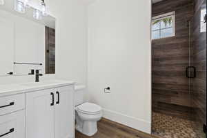 Bathroom with hardwood / wood-style floors, vanity, toilet, and a shower with door