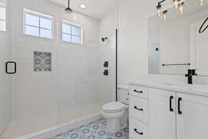 Bathroom featuring tile patterned floors, vanity, an enclosed shower, and toilet