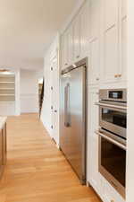 Kitchen featuring white cabinets, light hardwood / wood-style floors, and stainless steel appliances