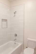 Bathroom with tiled shower / bath combo and toilet