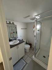 Bathroom with tile patterned floors, vanity, toilet, and an enclosed shower