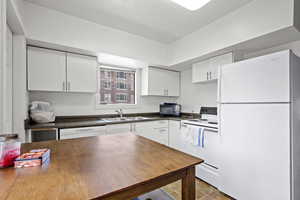 Kitchen featuring white appliances, white cabinetry, and sink