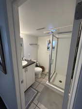 Bathroom featuring walk in shower, a textured ceiling, vanity, tile patterned flooring, and toilet