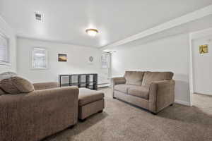 Carpeted living room featuring a wealth of natural light and a baseboard heating unit