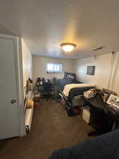 Bedroom with a textured ceiling and dark carpet