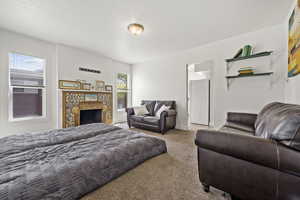 Carpeted bedroom with white fridge and a stone fireplace