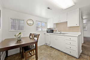 Kitchen featuring sink, a baseboard radiator, white dishwasher, decorative backsplash, and white cabinets