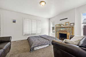 Carpeted bedroom featuring a stone fireplace