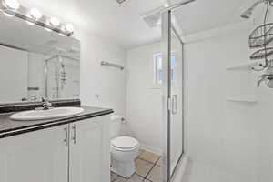 Bathroom with tile patterned floors, a shower with door, and vanity