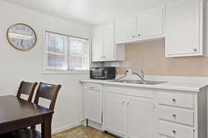 Kitchen featuring dishwasher, white cabinetry, sink, and tasteful backsplash