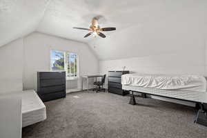 Bedroom with carpet flooring, ceiling fan, lofted ceiling, and a textured ceiling