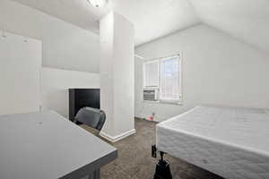 Carpeted bedroom with vaulted ceiling and cooling unit