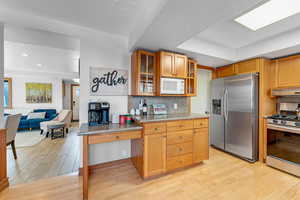 Kitchen featuring backsplash, range with gas cooktop, stainless steel refrigerator with ice dispenser, and light hardwood / wood-style floors