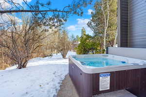 Snowy yard featuring a hot tub