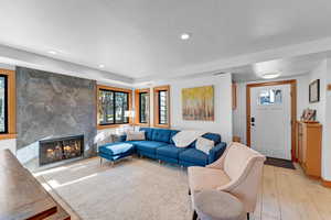 Living room with a fireplace, light hardwood / wood-style flooring, and a textured ceiling