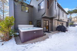 Snow covered back of property featuring a hot tub and central air condition unit