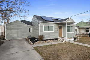 View of front of property with solar panels and a front lawn