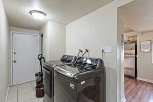 Laundry room with independent washer and dryer and light wood-type flooring