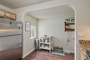 Kitchen featuring light brown cabinetry, light stone countertops, dark wood-type flooring, and stainless steel refrigerator