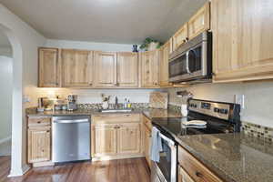 Kitchen featuring sink, light brown cabinets, dark hardwood / wood-style floors, and appliances with stainless steel finishes