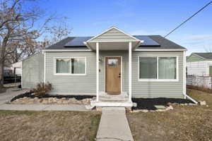 Bungalow-style home with a front yard and solar panels