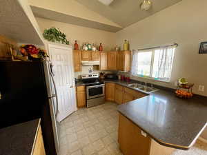 Kitchen with sink, kitchen peninsula, stainless steel appliances, and vaulted ceiling