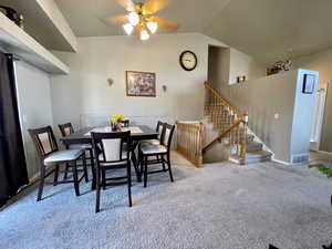 Dining area featuring ceiling fan, light carpet, and vaulted ceiling