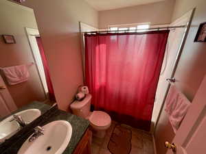 Full bathroom with tile patterned floors, shower / bathtub combination with curtain, vanity, and toilet