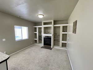 Unfurnished living room with a high end fireplace, a textured ceiling, and carpet flooring