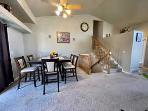 Dining room with ceiling fan, light carpet, and vaulted ceiling