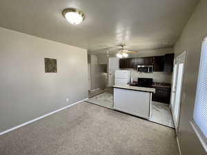 Kitchen with white refrigerator, light colored carpet, dark brown cabinetry, and black range oven