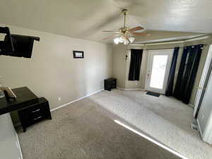 Unfurnished bedroom with a textured ceiling, ceiling fan, lofted ceiling, and carpet floors