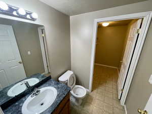 Bathroom featuring vanity, a textured ceiling, and toilet