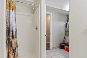 Bathroom featuring tile patterned flooring, curtained shower, and a textured ceiling