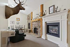 Carpeted living room featuring a fireplace and vaulted ceiling