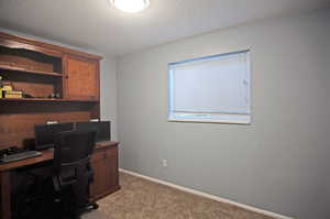 Office space featuring carpet flooring and a textured ceiling