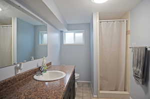 Bathroom with walk in shower, tile patterned flooring, a textured ceiling, toilet, and vanity