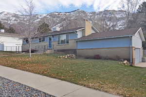 View of property exterior with a mountain view, a yard, and a garage