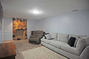 Living room with carpet, a textured ceiling, and a fireplace