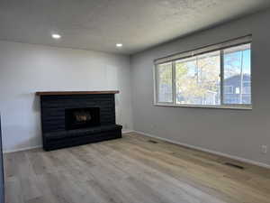 Unfurnished living room featuring a textured ceiling and light hardwood / wood-style flooring