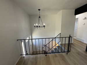 Stairs with hardwood / wood-style flooring and an inviting chandelier