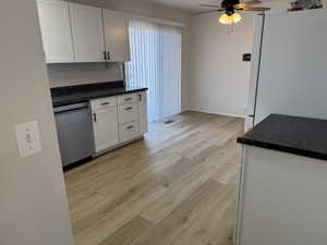 Kitchen featuring white refrigerator, white cabinetry, stainless steel dishwasher, and light hardwood / wood-style floors