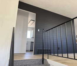 Staircase with wood-type flooring, a textured ceiling, and a package area