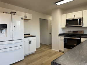 Kitchen featuring white cabinets, light hardwood / wood-style floors, and stainless steel appliances