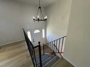 Foyer featuring a towering ceiling, a chandelier, and light wood-type flooring