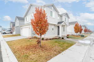 View of property with a front yard, a garage, and cooling unit